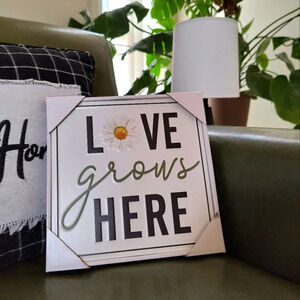 White yellow black metal sign Love Grows Here with a daisy on it home decor